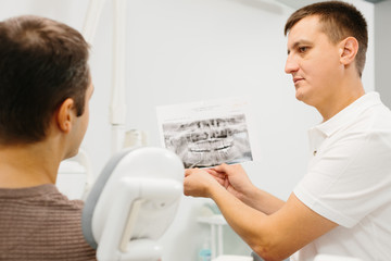 Obraz premium Dentist shows a patient x-ray of teeth