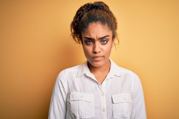 Fototapeta premium Young beautiful african american girl wearing casual shirt standing over yellow background skeptic and nervous, frowning upset because of problem. Negative person.