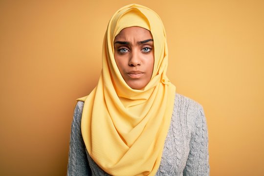 Young beautiful african american girl wearing muslim hijab over isolated yellow background depressed and worry for distress, crying angry and afraid. Sad expression.