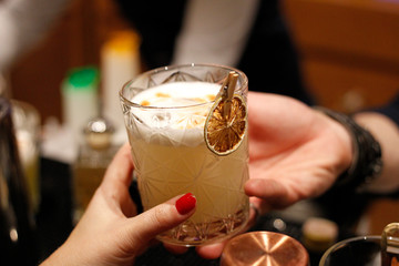 bartman serving a citrus cocktail in a client's hand