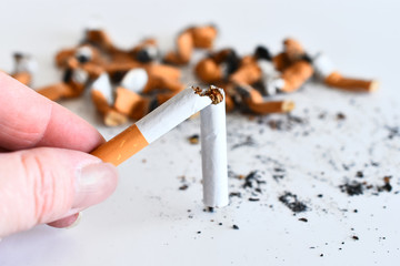 A close up image of a hand holding a broken cigarette. 