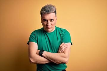 Young handsome modern man wearing casual green t-shirt over yellow background skeptic and nervous,...