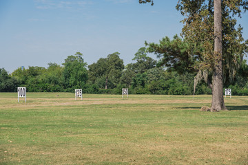 Golf course driving range yardage signs for 100, 125, 150 feet target on natural grass field