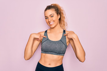 Fototapeta na wymiar Young beautiful blonde sportswoman with blue eyes doing exercise wearing sportswear looking confident with smile on face, pointing oneself with fingers proud and happy.