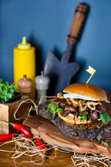 Beef steak burger medium well with mushrooms and cheese served on wooden board. Copy space.