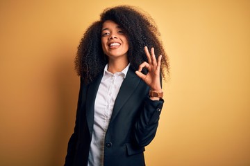 Young beautiful african american business woman with afro hair wearing elegant jacket smiling...