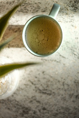 cup of coffee with a winged plant on a ceramic table