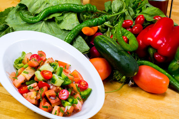 Various fresh mix salad leaves with tomato in bowl on wooden background