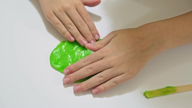 A boy playing with a green slime, kids fine motor skills, creativity and development, popular antistress toy