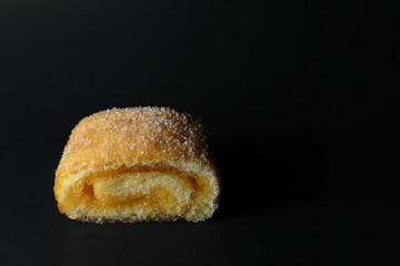 Rolled cakes filled with marmalade, orange, which are moist and bright, appetizing, and the top has sugar sprinkled within the darkness.