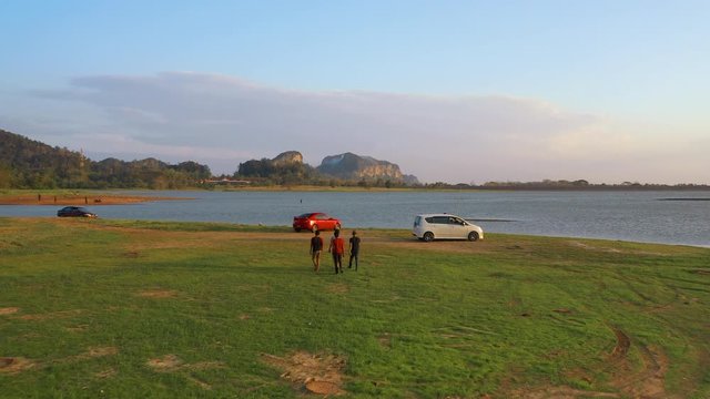 February 29th, 2020 - Perlis, Malaysia : 4k Aerial View of Unidentified people walking and enjoying beautiful sunset at Timah Tasoh Lake Side with Mountain View . Establishing , Drone Moving Forward