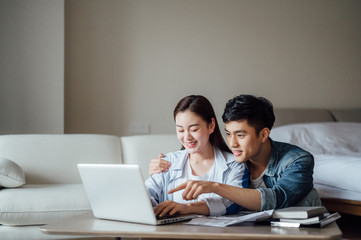 Young Asian couple at home using computer