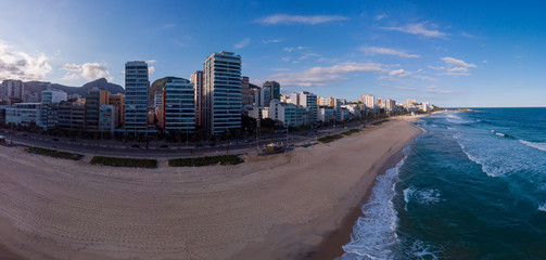 Near empty beach and boulevard of Ipanema in Rio de Janeiro during the COVID-19 Corona virus outbreak with blue sky over the Arpoador rock behind [April 13, 2020]