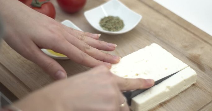Tagliare la feta greca per cucinare una ricetta mediterranea con pomodorini, olio e origano