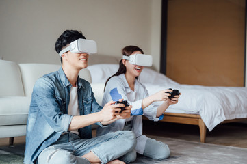 Young Asian couple wearing VR glasses to play games at home