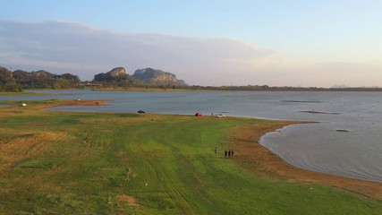 February 29th, 2020 - Perlis, Malaysia : 4k Aerial View of People Walking by Timah Tasoh Lake side During Beautiful Sunset with Mountain view. Establishing Shot, Drone Moving Forward
