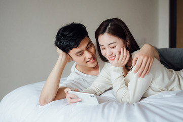 Young Asian couple at home using a smartphone