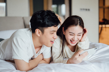 Fototapeta premium Young Asian couple at home using a smartphone