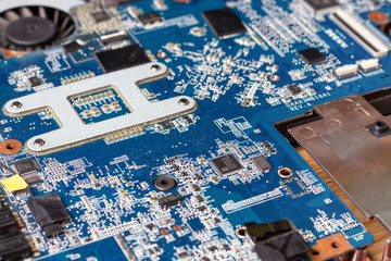 Motherboard and microcircuits on disassembled laptop close-up top view.