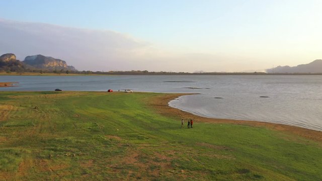 February 29th, 2020 - Perlis, Malaysia : 4k Aerial View of Unidentified people walking and enjoying beautiful sunset at Timah Tasoh Lake Side with Mountain View . Establishing , Drone Tracking Left
