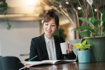 Young woman asian with laptop online learning. Lifestyle social distance education. Development skills by yourself. Lady asian in workplace office modern business. Green corporate environment.