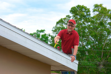 Wind mitigation inspection inspector on a ladder doing inspection on new roof to create a report and risk rating for homeowner to send to their insurance company to receive deductions in policy costs. - 338641533