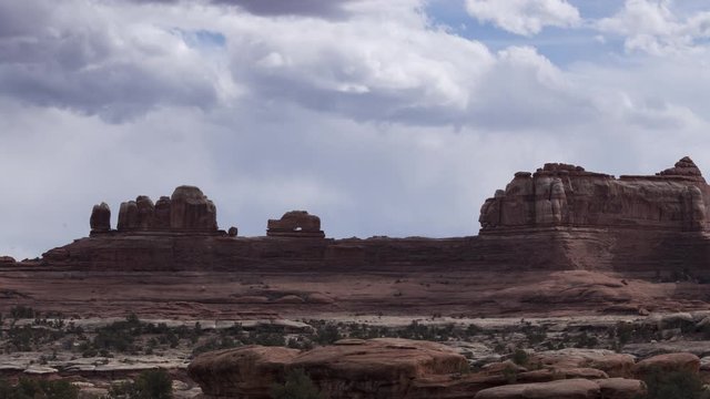 A long-lens timelapse looking towards Wooden Shoe Rock in the Needles District of Canyonlands National Park. Clouds flow overhead at speed.