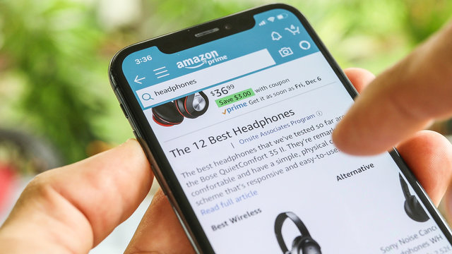 NEW YORK CITY, NY  December 1, 2019: Man searching Headphones on Amazon app with Mobile Smart iPhone