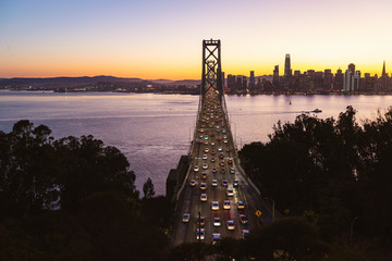 Beautiful golden sunset behind the San Francisco city while traffic stands still on the iconic Golden Gate Bridge.  
