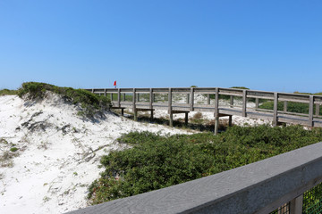 beach boardwalk over sand dunes with blue sky background at santa rosa florida state park 