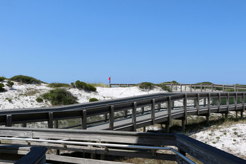 beach boardwalk over sand dunes with blue sky background at santa rosa florida state park 