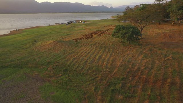 February 29th, 2020 - Perlis, Malaysia : 4k Aerial View of Unidentified people walking and enjoying beautiful sunset at Timah Tasoh Lake Side with Mountain View . Establishing , Drone moving Backward