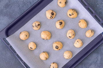 Baking tray with uncooked cookies on dark background