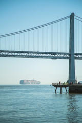 The famous Golden Gate Bridge shot at midday. The image of the bridge is reflected in the water on the sand. 