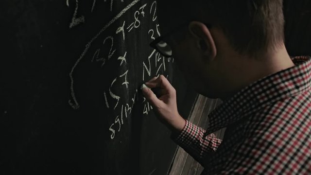 man writes math formula on blackboard