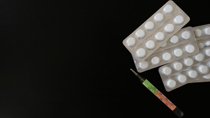 pills from coronavirus on a black background. insulation. thermometer on a black background