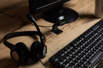 Home office theme: Close-up of headband with microphone and computer on wooden desk background. concept of online work and video calls.