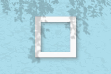The square frame on the blue wall background. Mockup overlay with the plant shadows. Natural light casts shadows from the tree's foliage. Flat lay, top view
