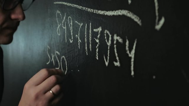 man writes math formula on blackboard