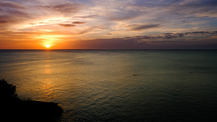 Two surfers crossing the ocean at sunset