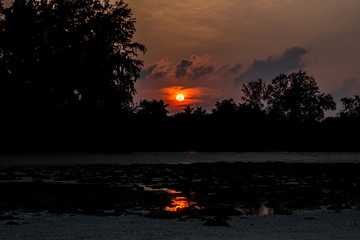 A shot of Beach silhouette with interesting cloudscape and sun and its reflection