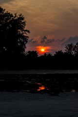A portrait shot of Beach silhouette with interesting cloudscape and sun and its reflection