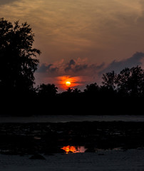 A portrait shot of Beach silhouette with interesting cloudscape and sun and its reflection