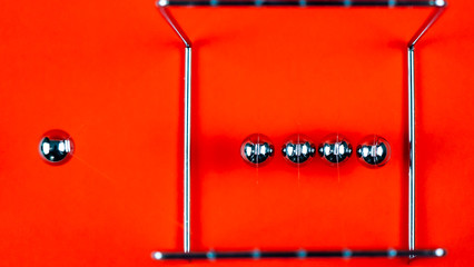Newtons cradle metal balls moving on orange background