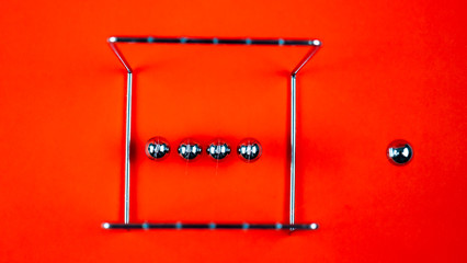 Newtons cradle metal balls moving on orange background