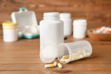 Fototapeta na wymiar Bottles with pills on wooden background