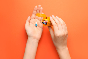 Female hands with bottle and pills on color background