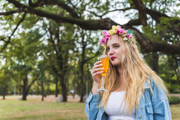Woman holding a soft drink glass and drinking soda, coke or beer outdoor in the park