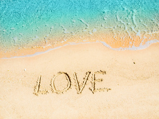 Inscription on yellow sand written by finger, close up view. Red Sea beach in Egypt. Nature background. Selective soft focus. Blurred background