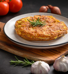 Spanish omelette with potatoes and onion and ingredient Spanish cuisine. Tortilla espanola. Rustic dark background